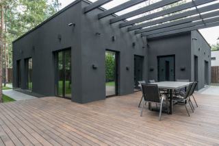Pergola bioclimatique à lames orientables sur une terrasse Pergola bioclimatique en aluminium anthracite, lames orientables entrouvertes au-dessus d'une terrasse